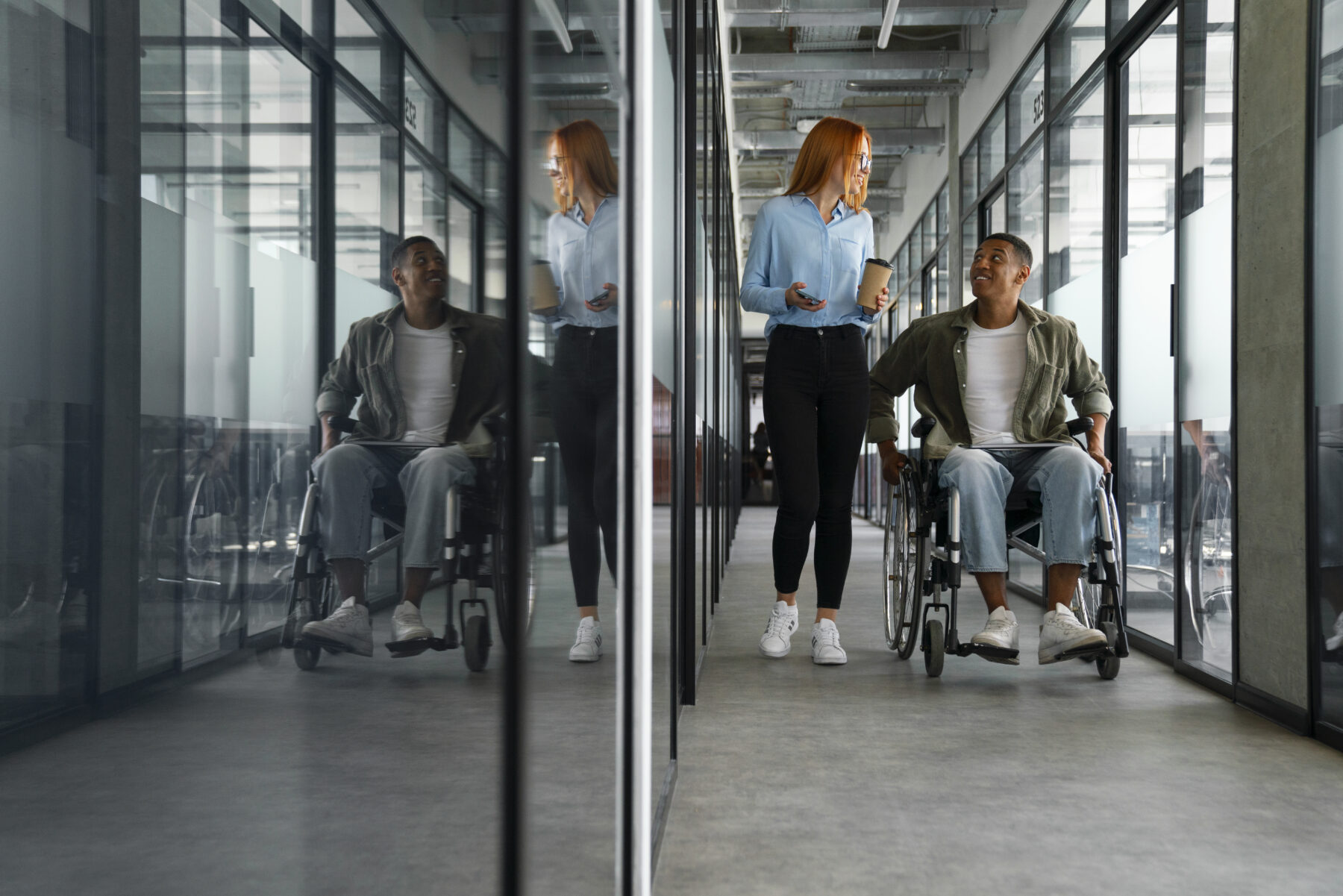 A man in a wheelchair is walking with a woman in an office.
